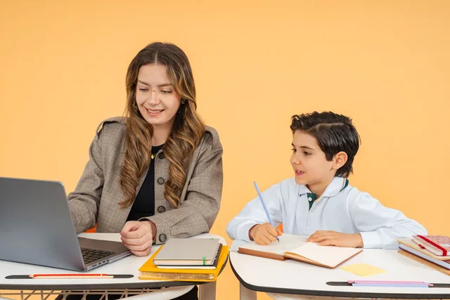 Una profesora y un niño trabajan juntos con un portátil.